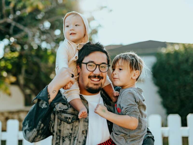 Père et ses deux enfants souriants en extérieur