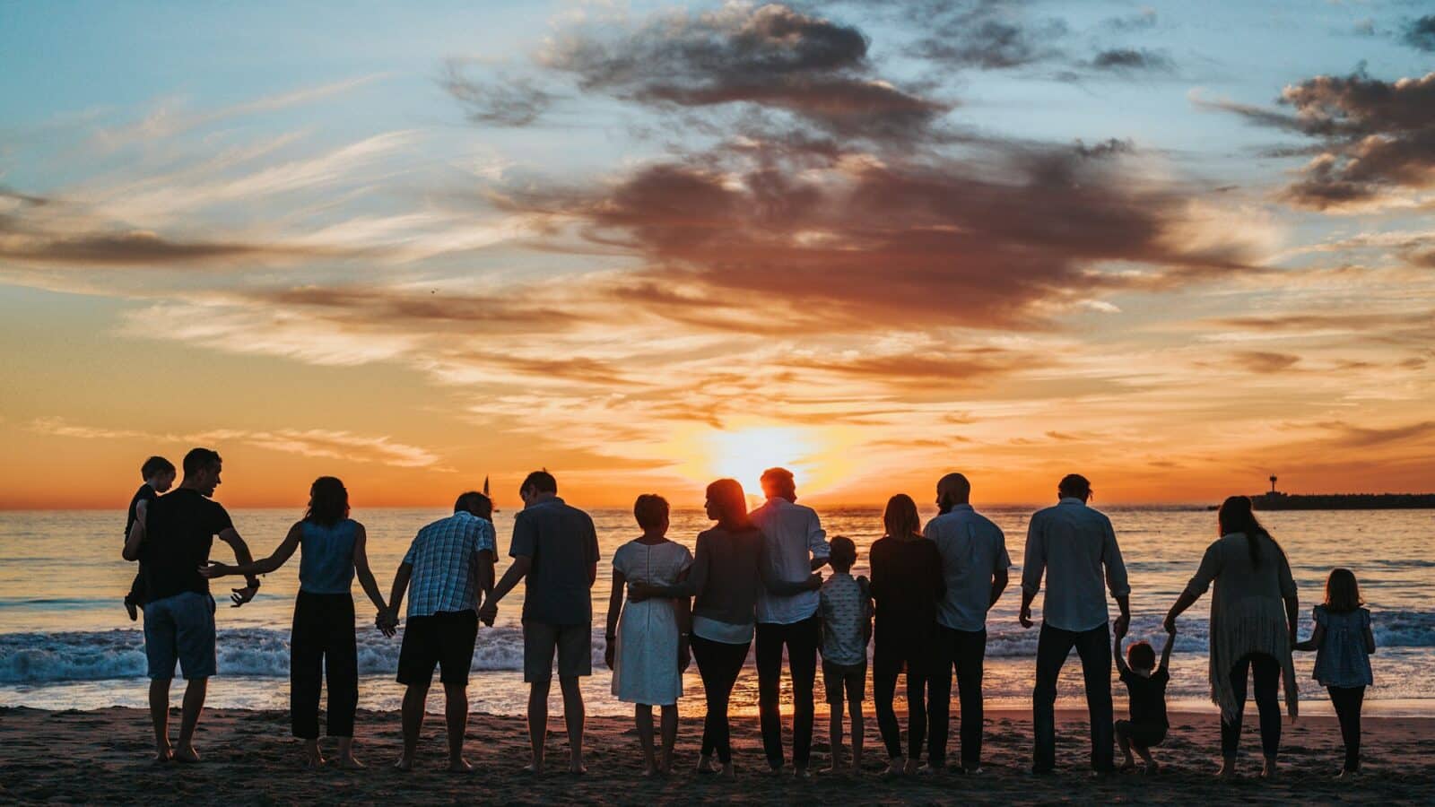 Famille main dans la main sur la plage au coucher du soleil