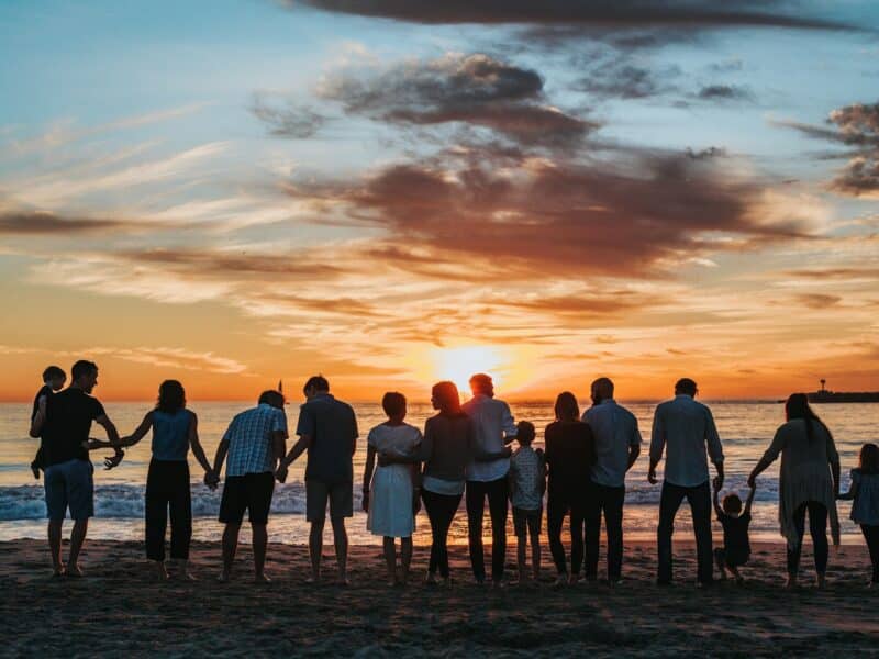 Famille main dans la main sur la plage au coucher du soleil