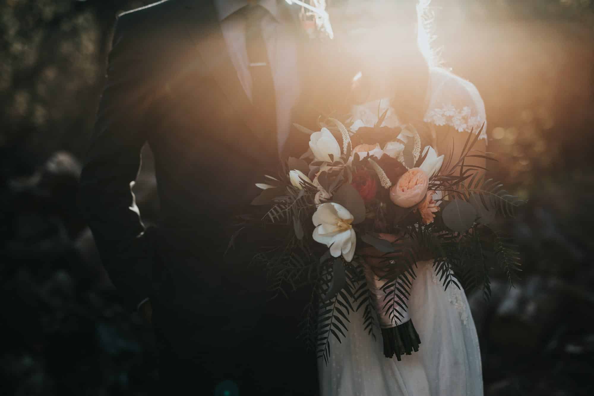 Mariée tenant son bouquet dans une lumière de fin de journée